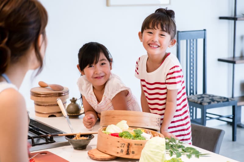 料理する母親と楽しそうに会話する女の子