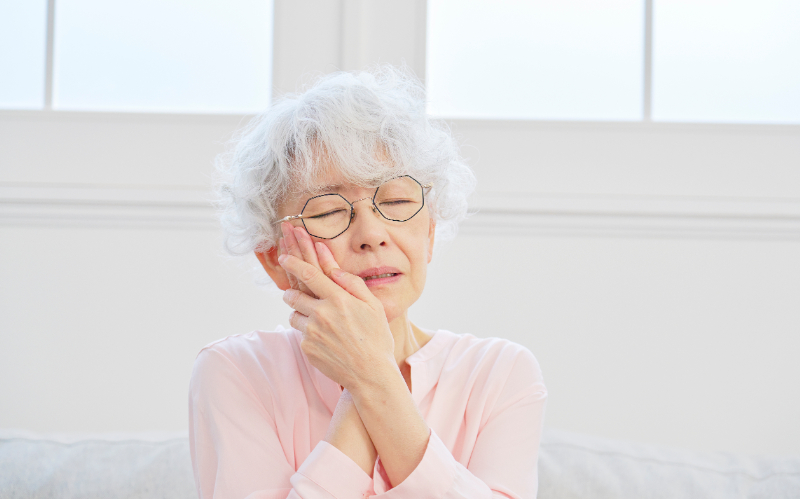 入れ歯が合わず歯ぐきに痛みを感じる女性