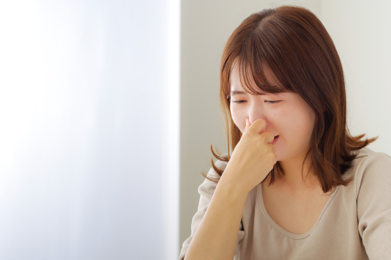 口臭が気になり鼻をつまむ女性