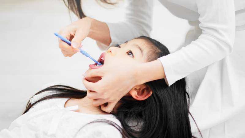 親に仕上げ磨きをしてもらう子ども