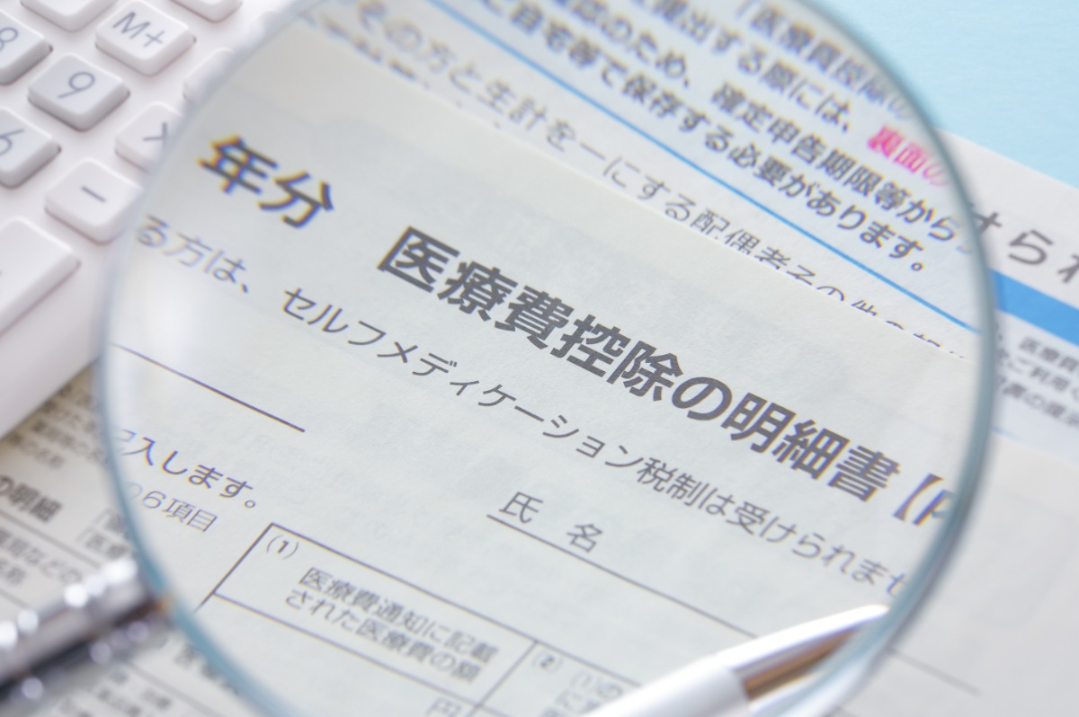 医療費控除の申請書を虫眼鏡で見ているイメージ